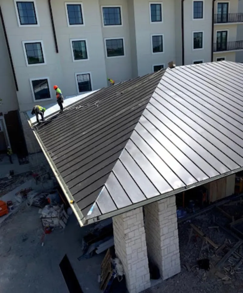 Crew installing standing seam metal roof panels on a commercial project in Frankfort Square